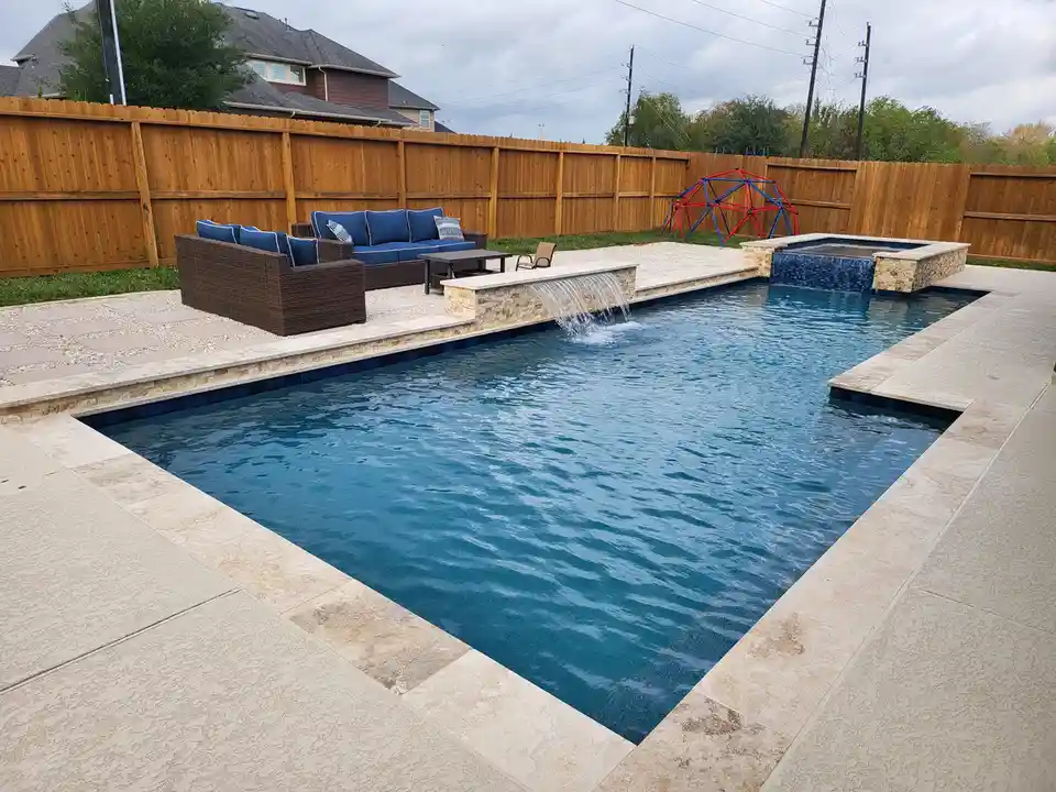A professionally landscaped backyard features a large, rectangular swimming pool with a stone waterfall feature and a…