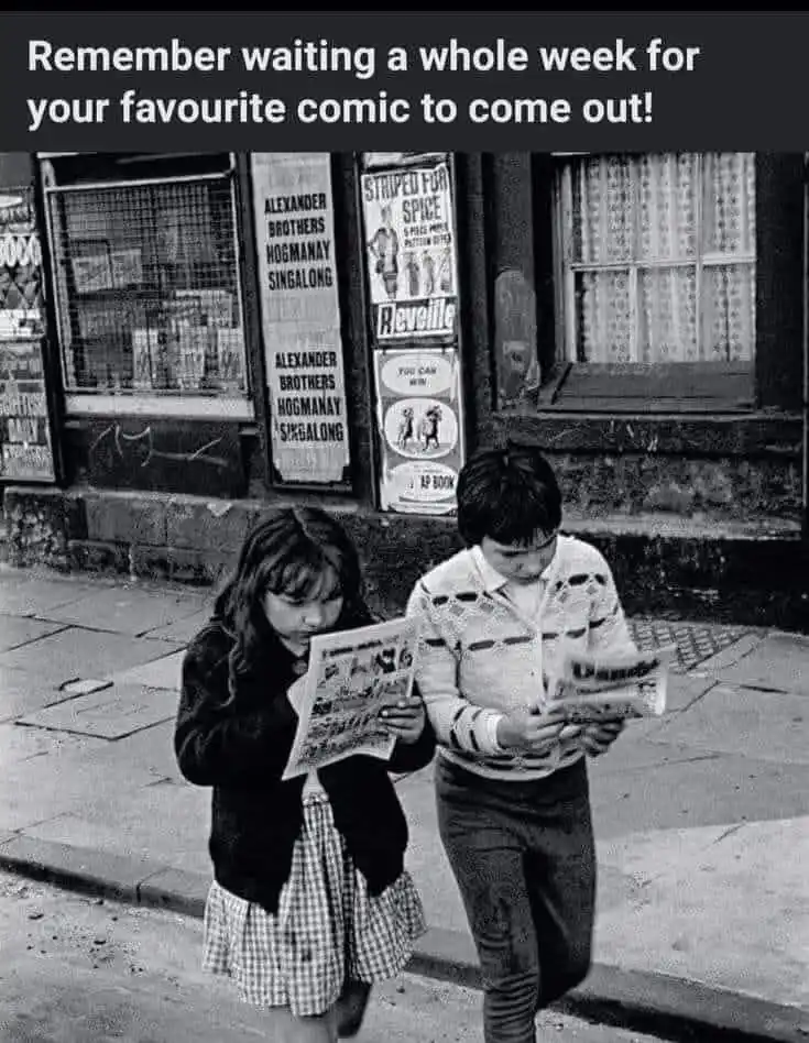 A black-and-white photo shows two children, a girl in a checkered skirt and a boy in a patterned sweater, standing on a…
