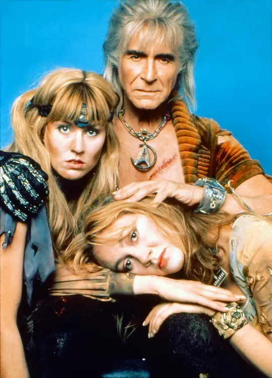 A promotional photo of the 1980s TV show 'Fame' features three actors posing against a solid blue background. The central…