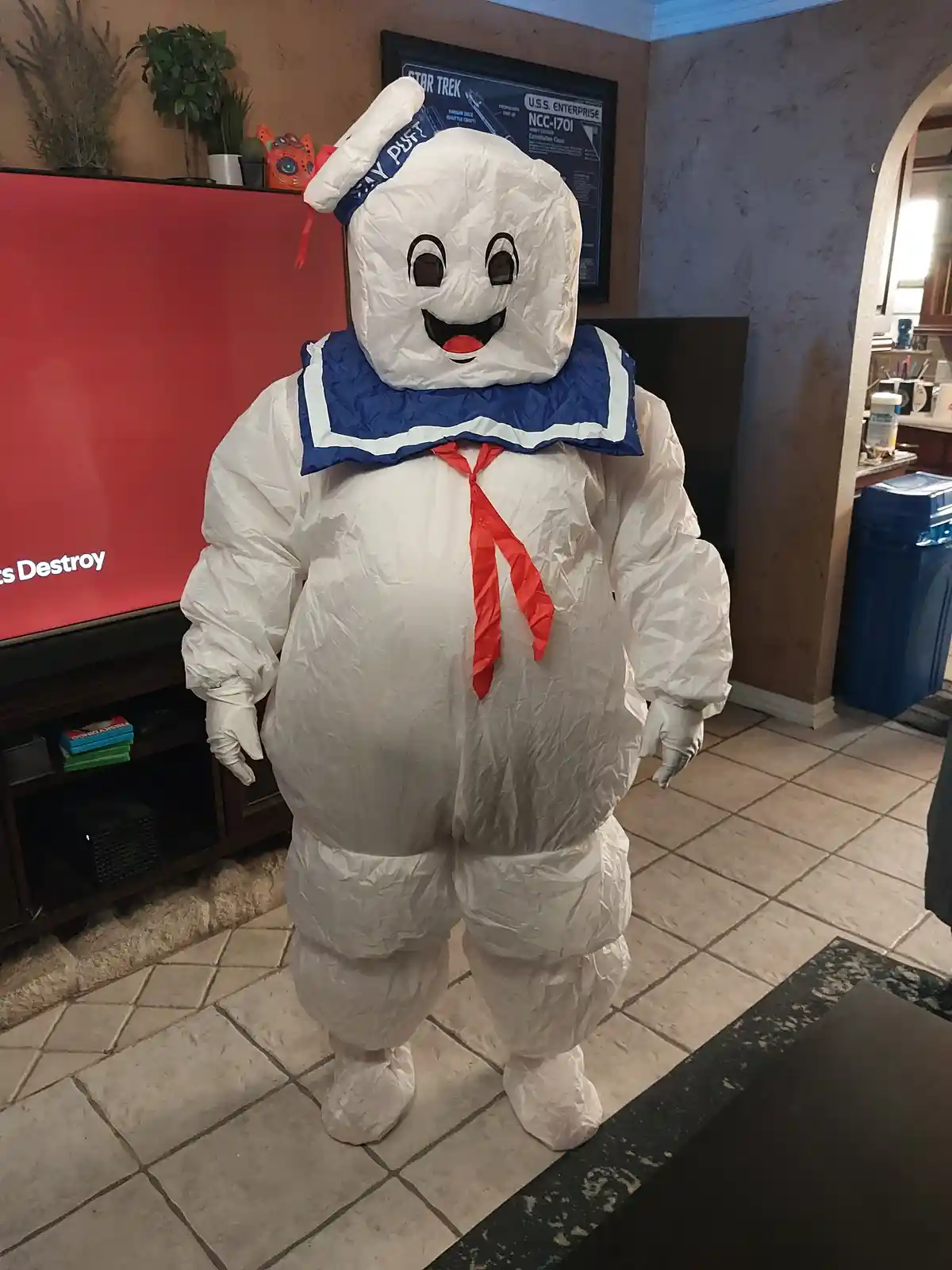 A person in a full-body, white, puffy costume resembling the character Stay Puft Marshmallow Man from Ghostbusters stands…