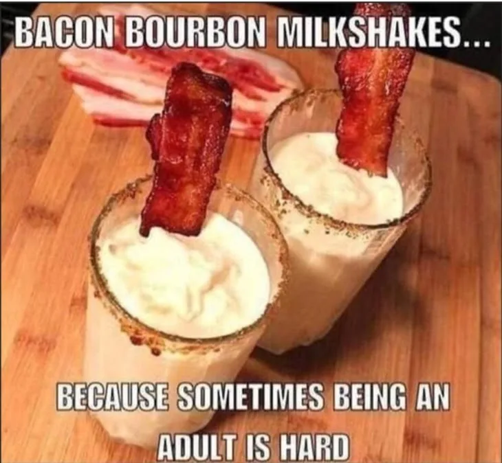 Two glasses filled with creamy milkshakes, each garnished with a crispy strip of bacon stuck into the top, sit on a wooden…