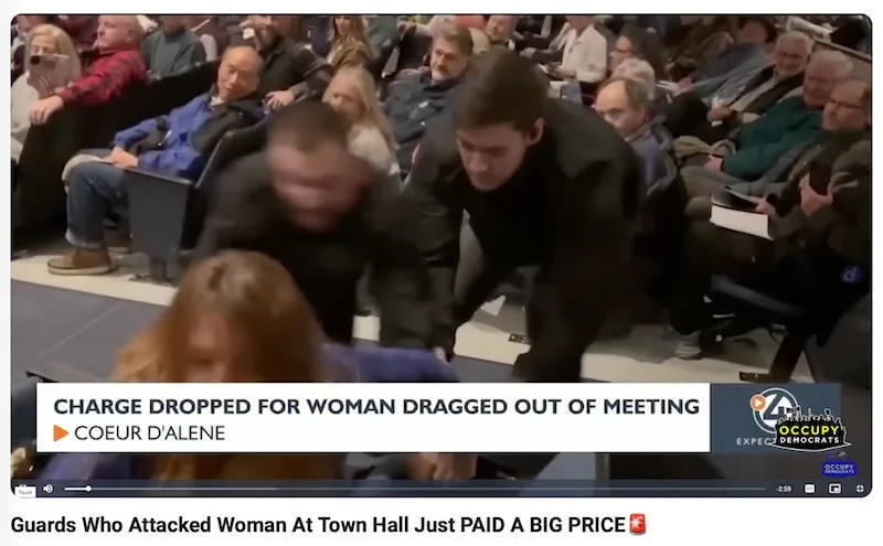 A video still shows two men in dark jackets physically dragging a woman out of a seated audience at a town hall meeting…