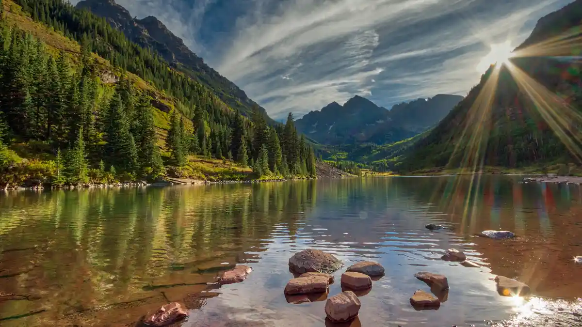 Gaze across Maroon Lake in Colorado at the majestic Maroon Bells, two "fourteeners" with peaks rising in the distance…