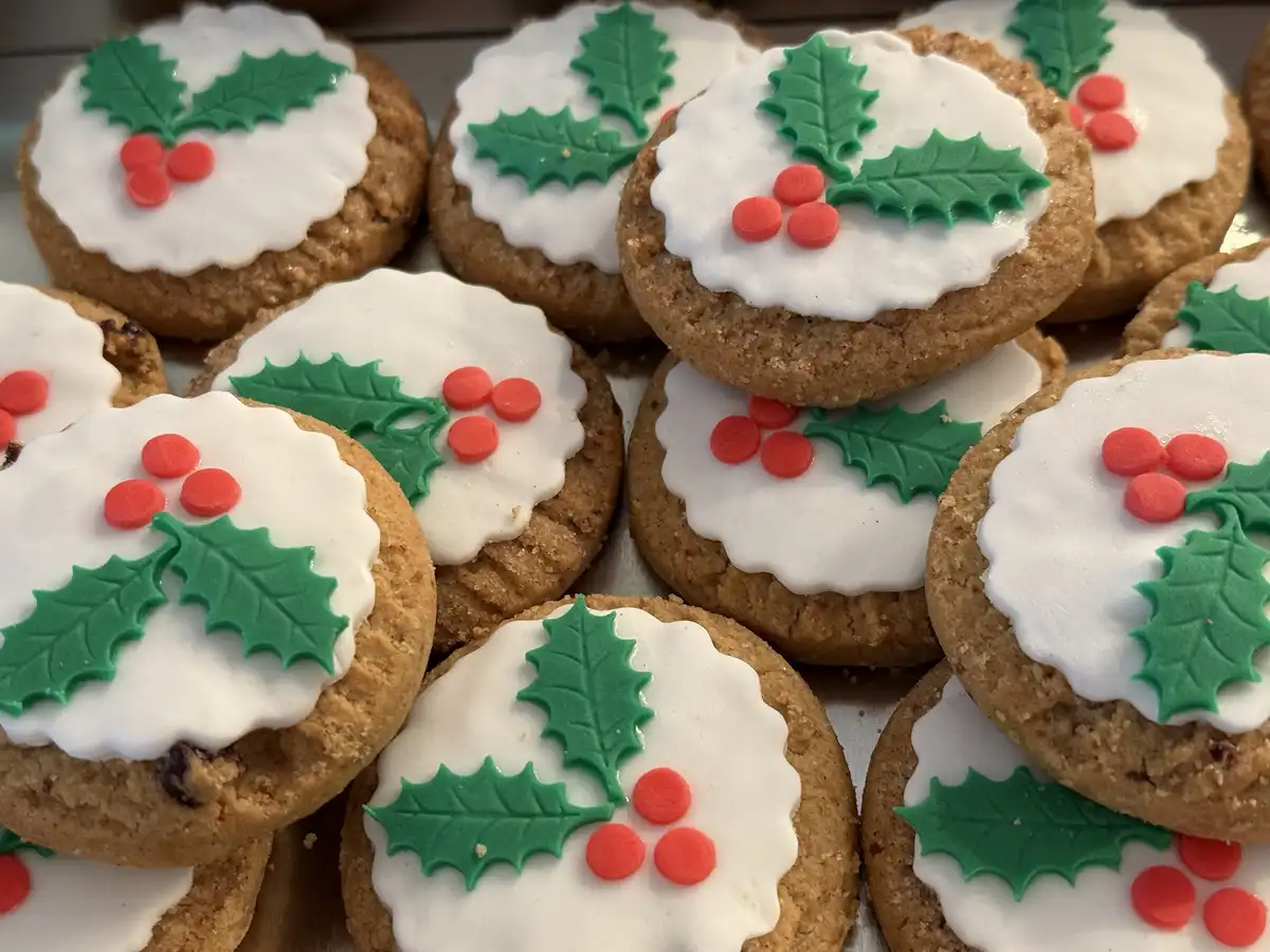 A close-up photo shows numerous round, golden-brown cookies arranged closely together. Each cookie is topped with a dollop…