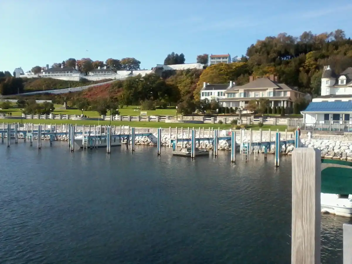 A scenic waterfront view shows a calm body of water with a wooden pier and several docked boats. On the shore, there are…
