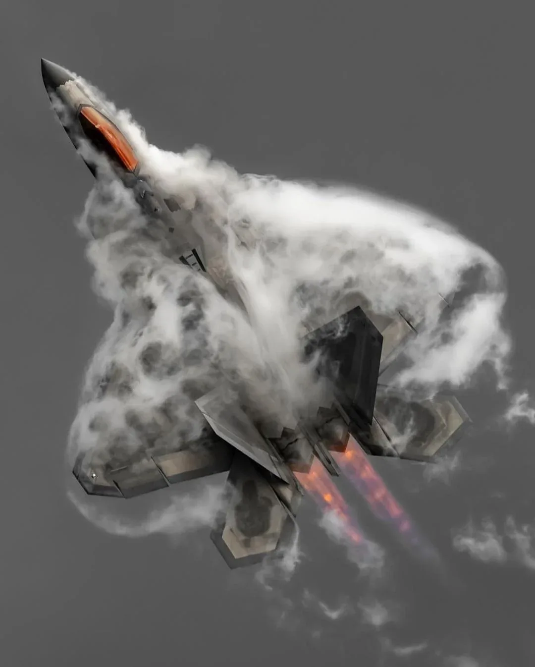 A fighter jet, likely an F-22 Raptor, is shown in a steep upward climb, surrounded by a thick cloud of white vapor or smoke…