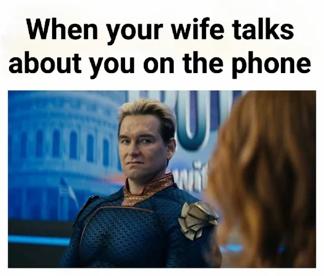 A man in a blue superhero costume with a stern, slightly annoyed expression looks toward a woman with red hair whose back is…