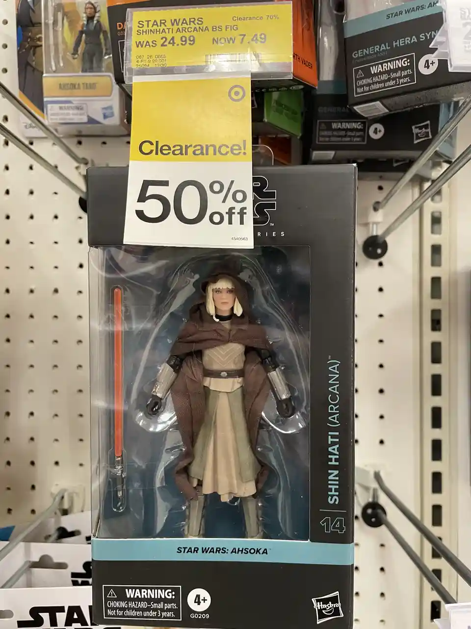A Star Wars action figure of Shin Hati (Arcana) from the Ahsoka series is displayed on a store shelf with a prominent yellow…