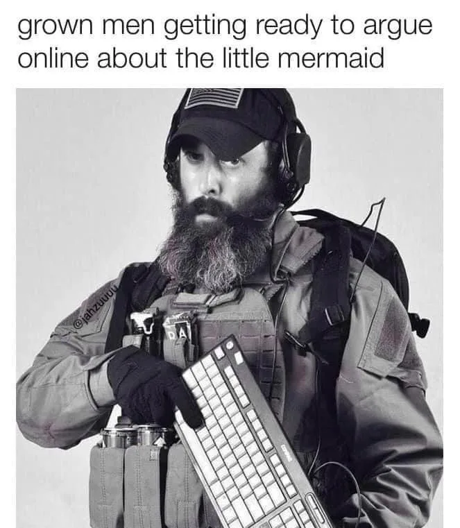 A black-and-white photo shows a bearded man in tactical gear, including a cap, headset, and vest, holding a computer…