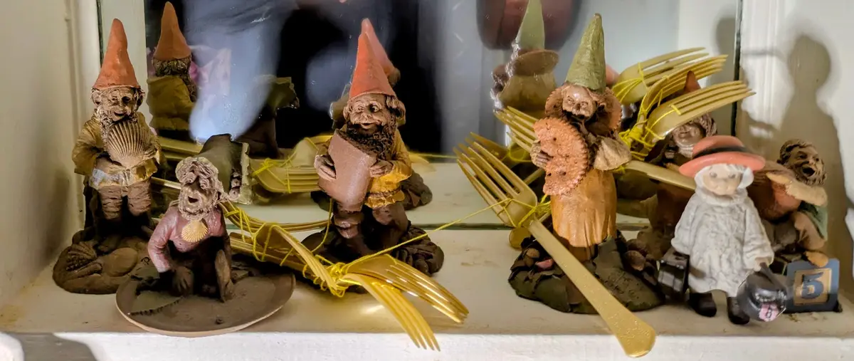 A collection of garden gnome figurines is displayed on a windowsill, with several of them having their heads replaced by…
