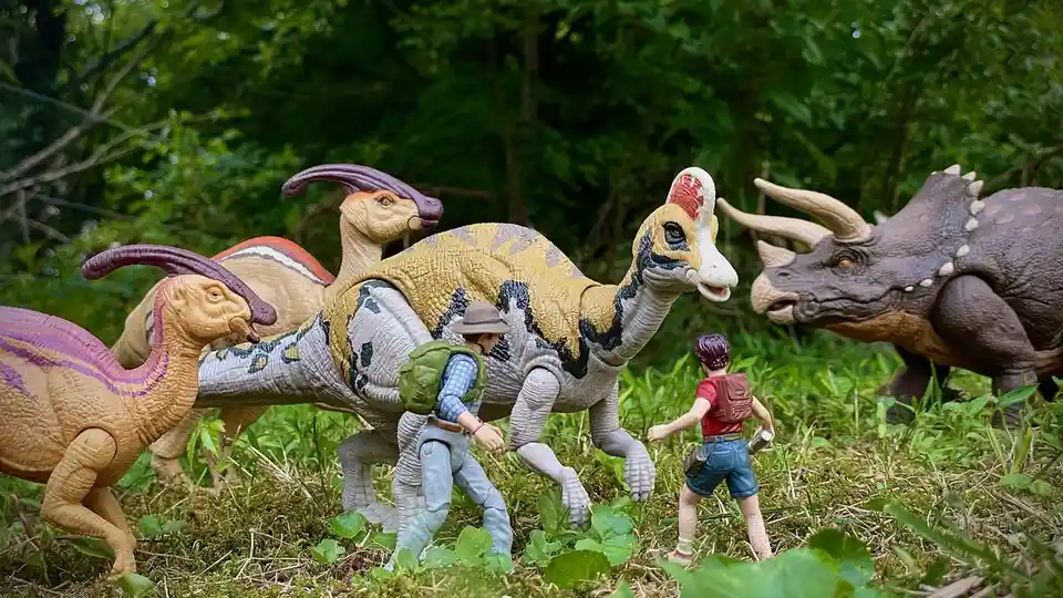 A photo of toy dinosaurs and two toy human figures in a grassy outdoor setting. The overlaid text reads 'i'm not scared of…