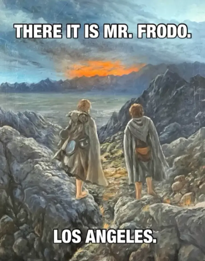 Two characters from The Lord of the Rings stand on a rocky mountain ridge overlooking a vast valley with distant mountains…