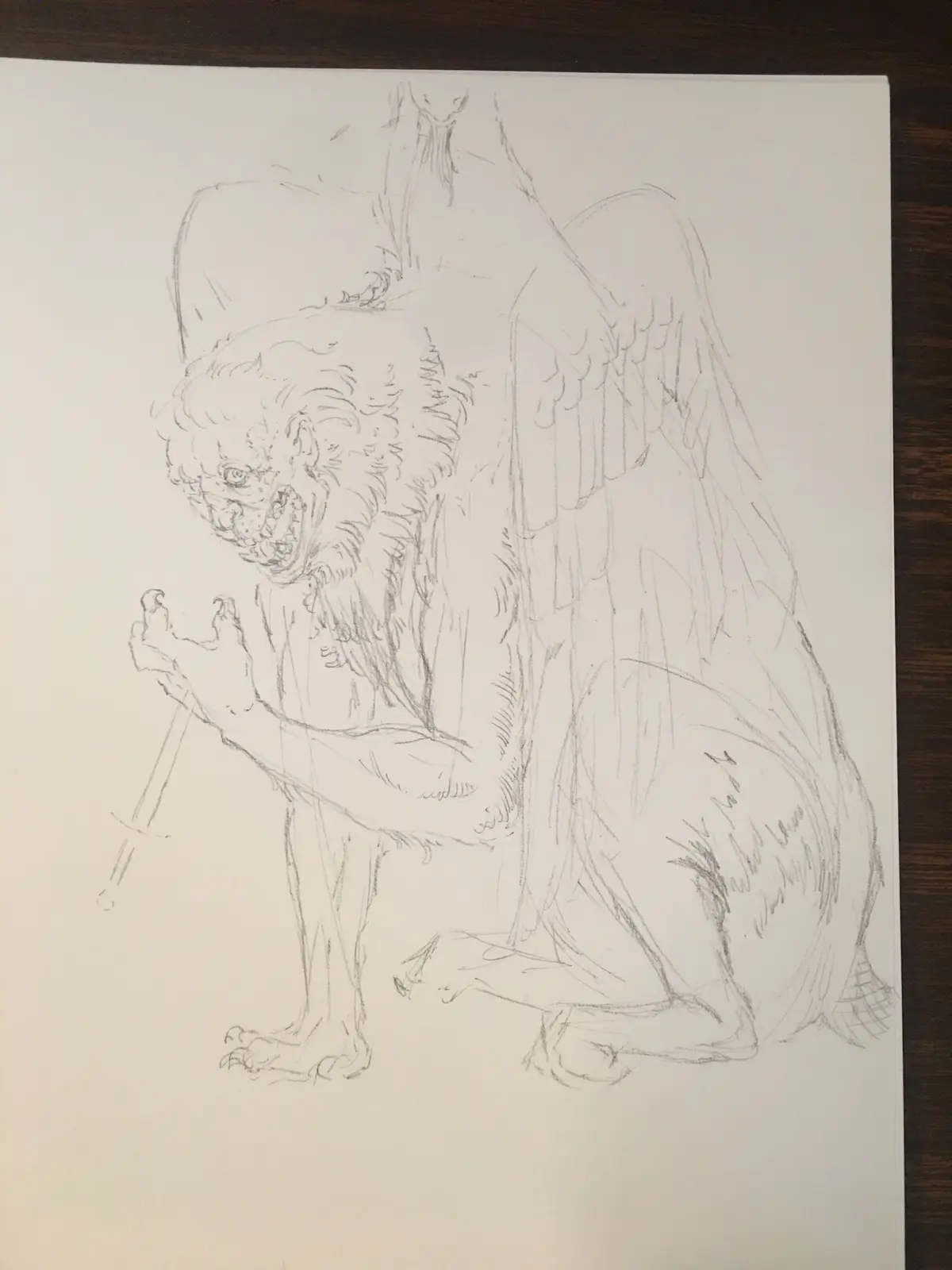 A pencil sketch on white paper depicts a grotesque, winged demon-like creature with a hunched posture, sharp teeth, and…