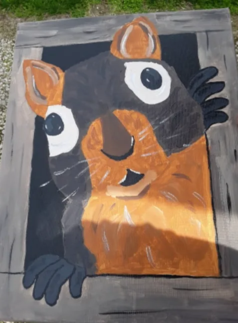 A hand-painted mural on a wooden surface depicts a cartoonish chipmunk with large white-rimmed eyes, orange-brown fur, and…