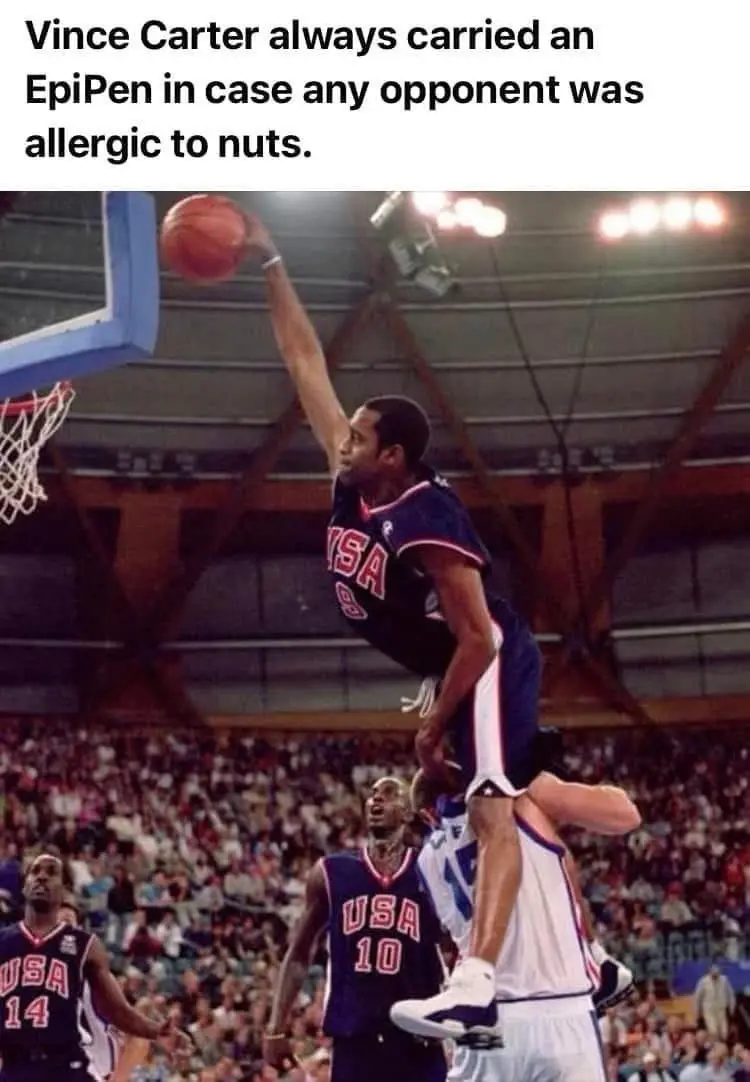 A basketball player, Vince Carter, is captured mid-air performing a dunk in a USA jersey, with other players and a crowd…