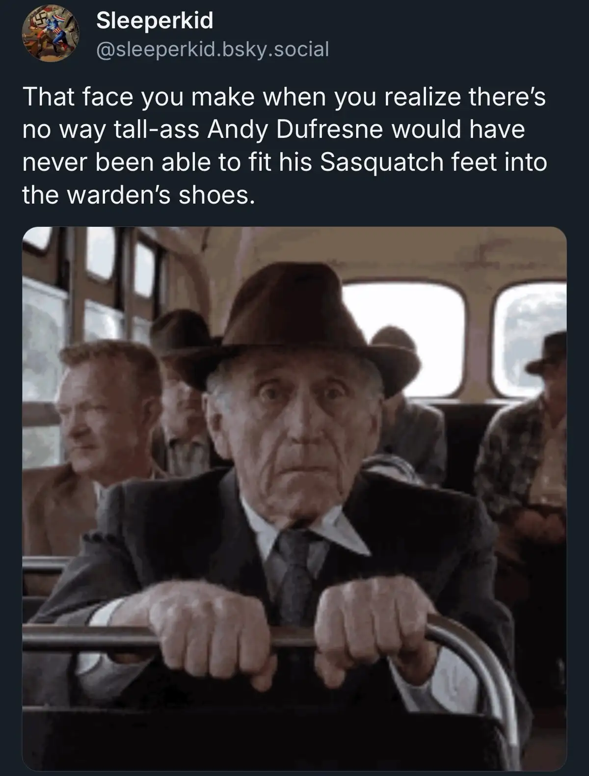 An older man in a suit and fedora grips a metal bar with a shocked, wide-eyed expression while seated on a bus. The overlaid…