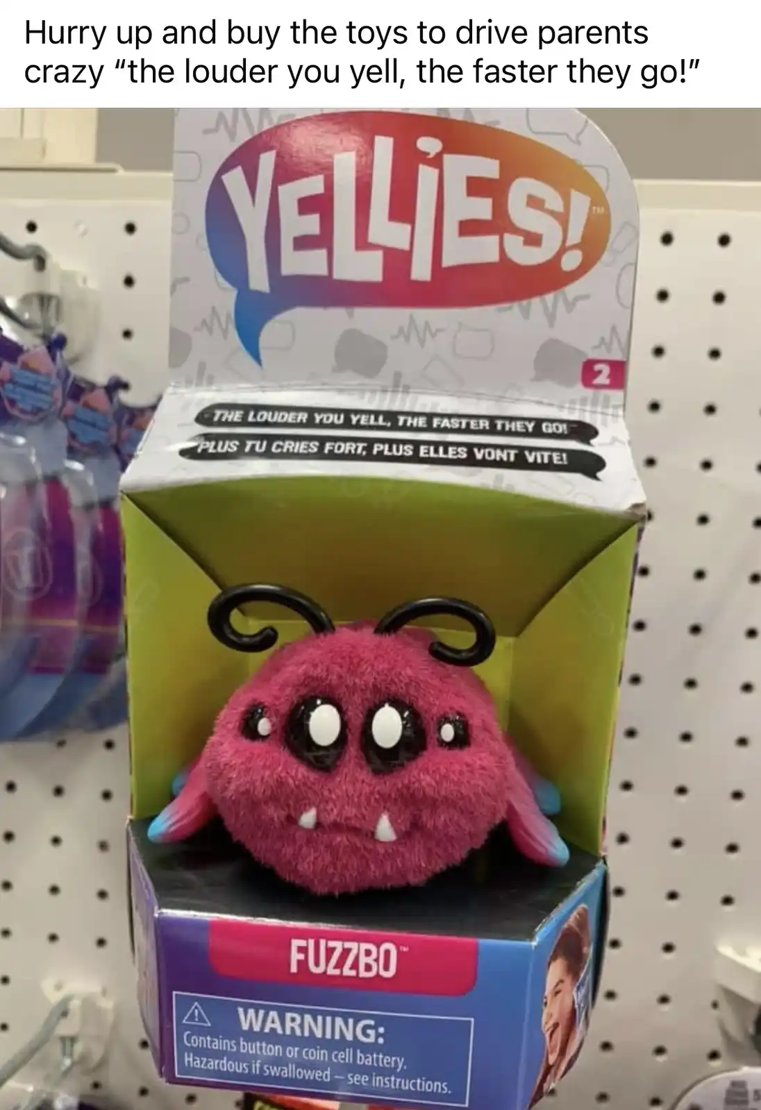 A pink, fuzzy, bug-like toy named 'Fuzzbo' sits in its retail box on a store shelf. The box prominently displays the brand…