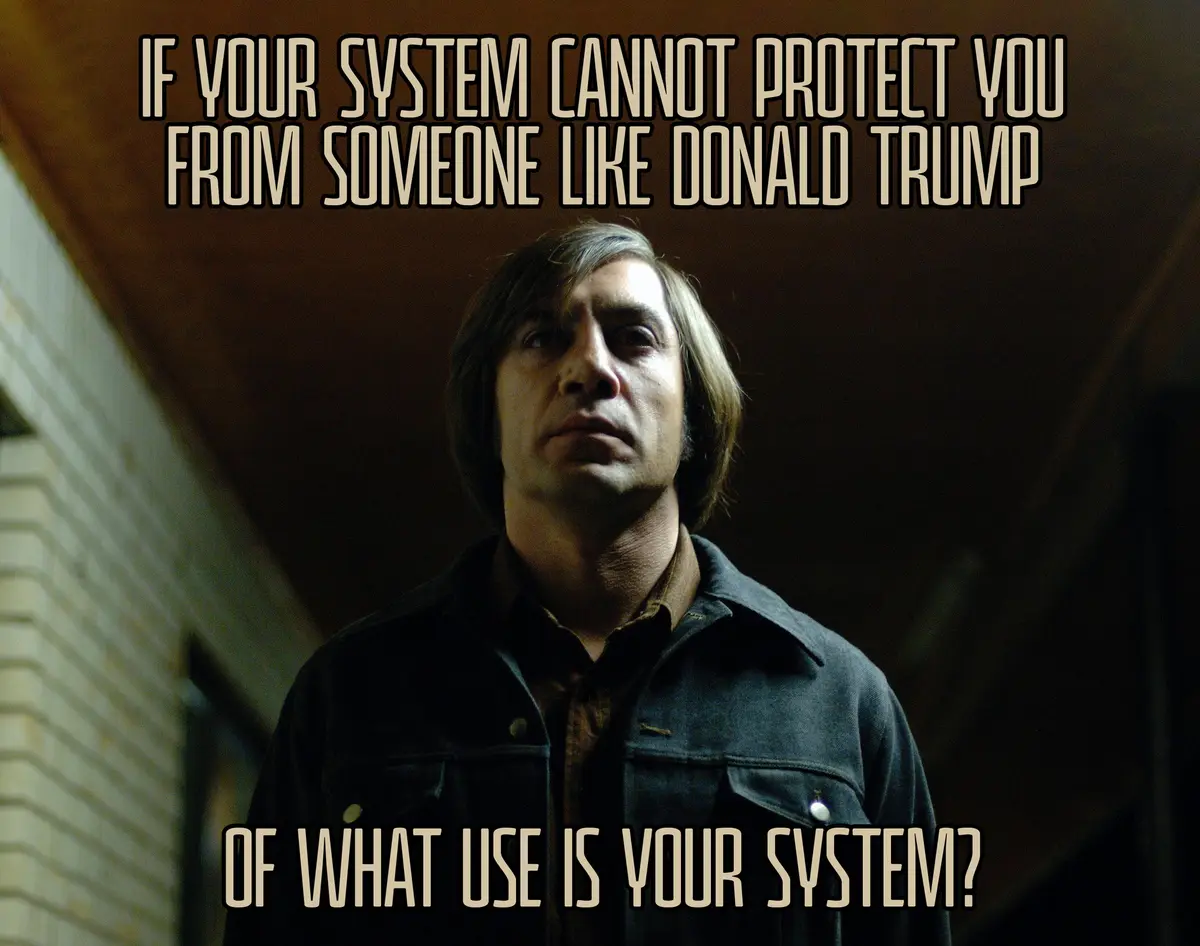 A man with shoulder-length hair and a dark jacket looks upward with a serious expression. The image has two lines of text…