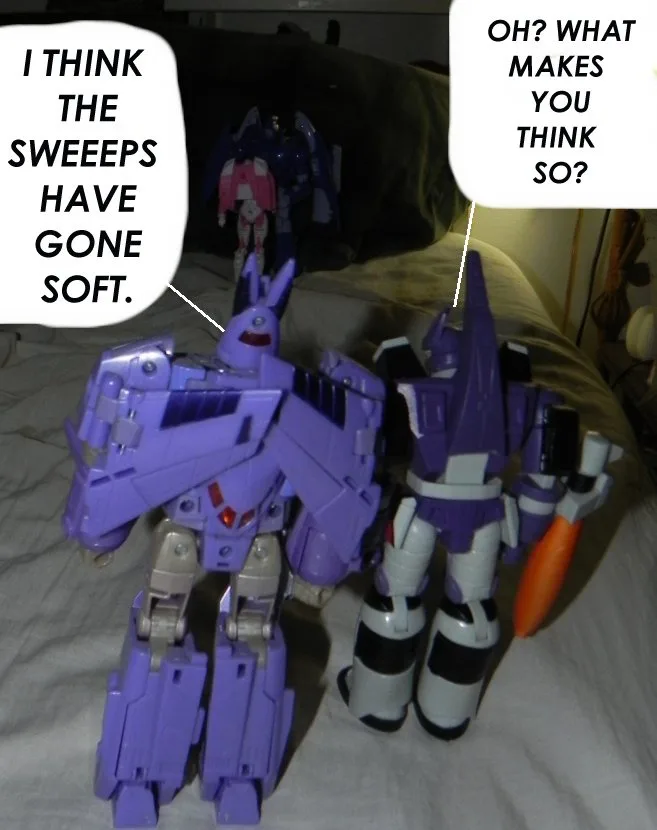 Two purple Transformers action figures stand on a bed, one with a speech bubble saying 'I THINK THE SWEEEPS HAVE GONE SOFT.'…