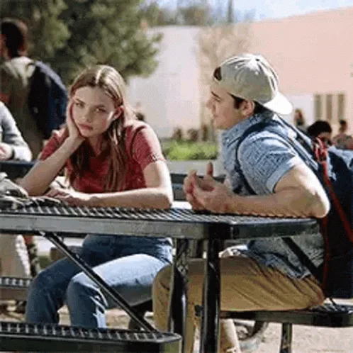 A grid of six panels shows a young woman in a red shirt sitting at a metal picnic table outdoors, reacting to a boy beside…