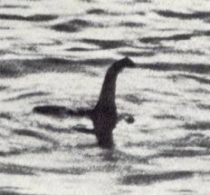 A grainy black-and-white photo shows a long-necked, dark silhouette emerging from rippling water, resembling the mythical…