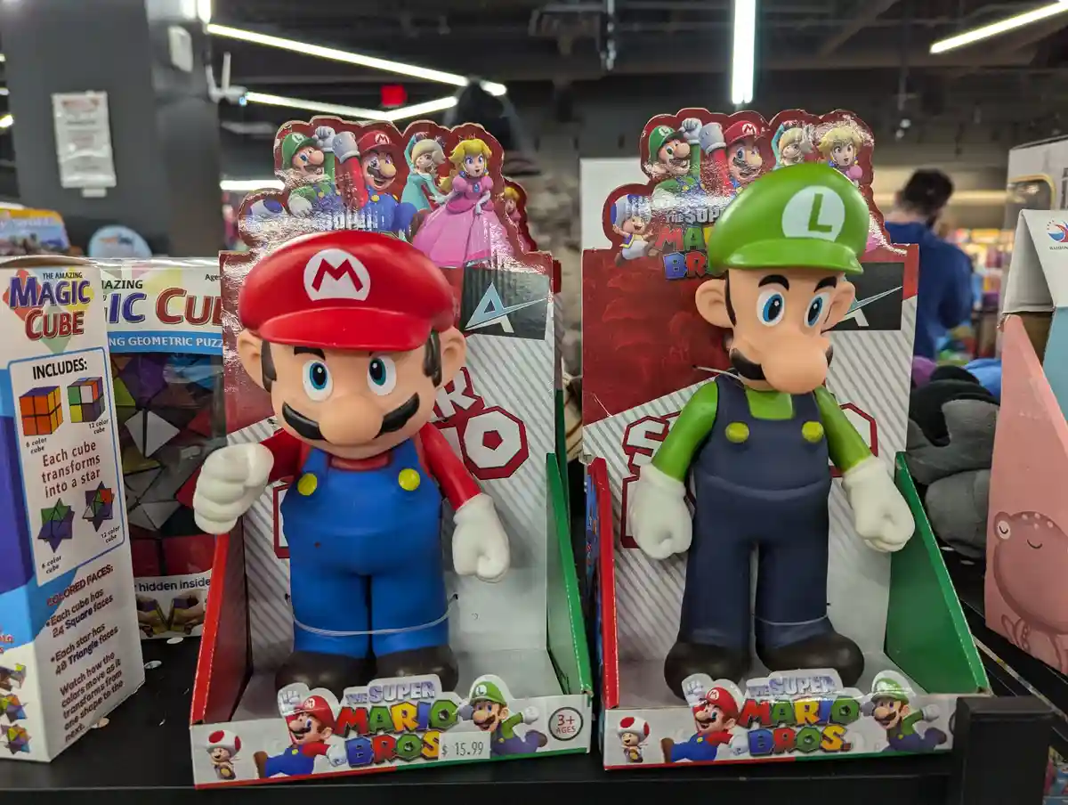 Two large plastic Super Mario Bros. action figures, Mario in red and Luigi in green, are displayed side by side in their…
