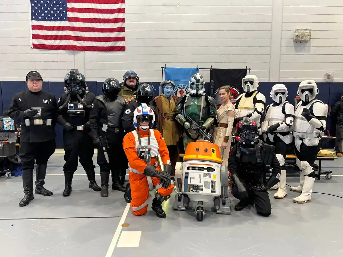 A group of people dressed as Star Wars characters, including stormtroopers, rebels, and droids, pose for a photo in a…