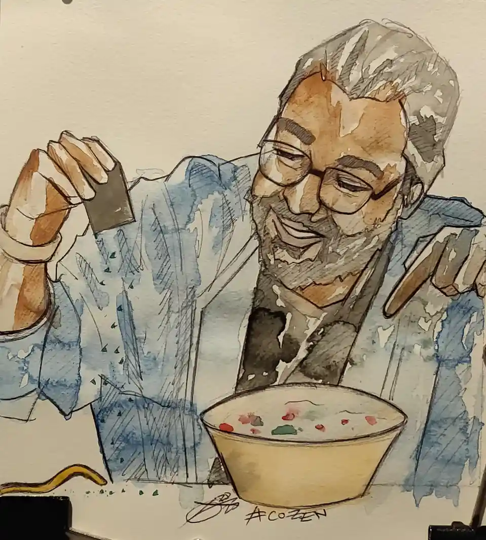 A watercolor illustration shows a smiling man with glasses and a beard, wearing a blue shirt, holding a small dark square…