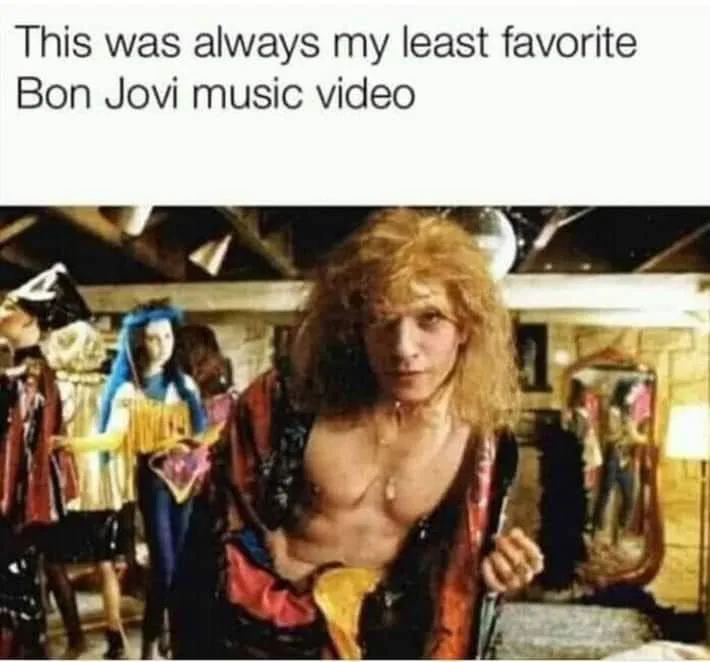 A still from a Bon Jovi music video shows a shirtless man with long, messy blonde hair looking directly at the camera. He…