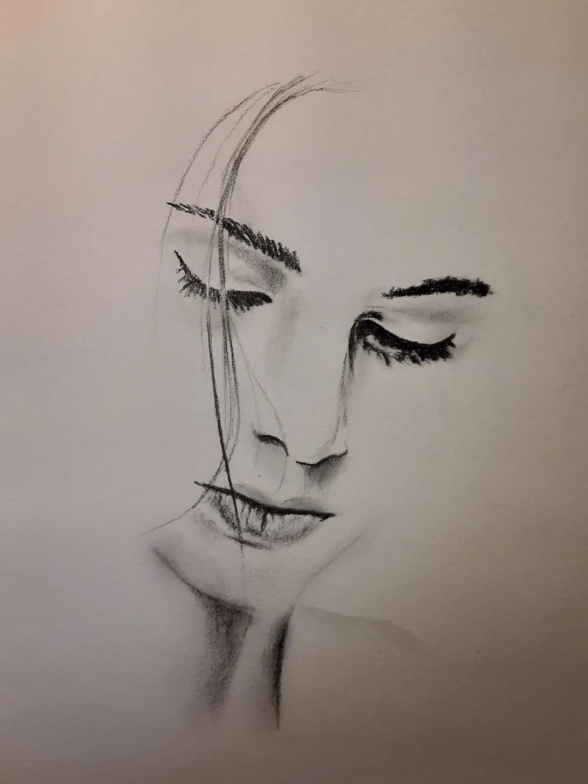 A black-and-white charcoal sketch of a person's face with closed eyes and a serene expression, featuring a single strand of…