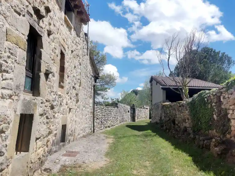A sunlit, narrow stone path between old buildings under a blue sky with clouds, with overlaid text reading 'i'm not lazy…