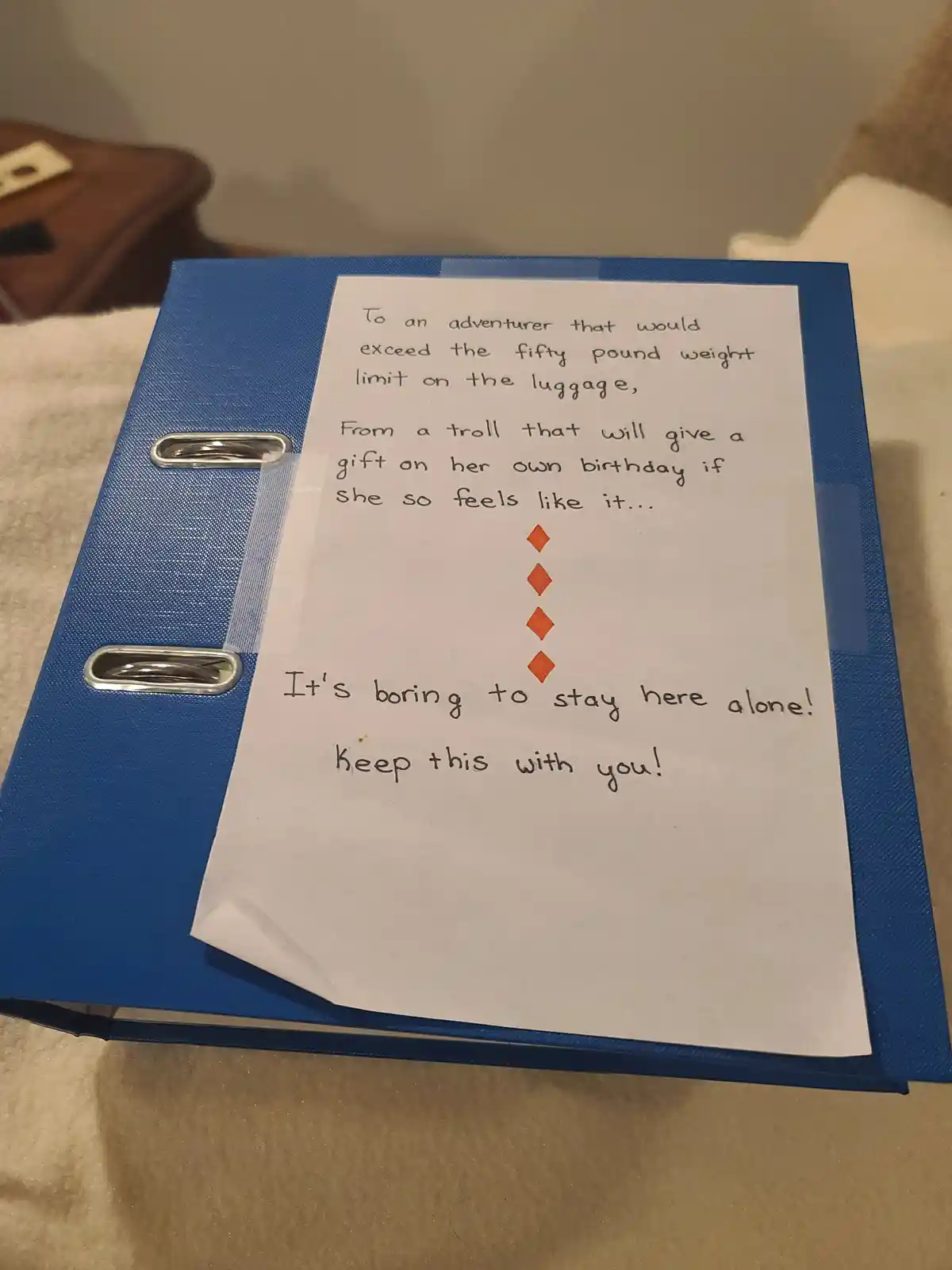 A handwritten note taped to a blue binder reads a playful, slightly sarcastic message addressed to an adventurer who exceeds…