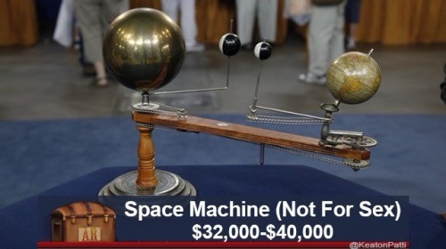 A vintage mechanical orrery with three spheres on a wooden arm, displayed on a blue cloth. Overlaid text reads 'Space…