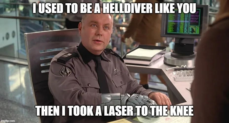 A man in a grey uniform with a mechanical prosthetic arm sits at a desk in an office setting, looking at someone off-camera…