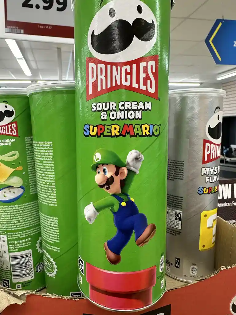 A green Pringles can featuring Luigi from Super Mario, labeled 'Sour Cream & Onion Super Mario', is displayed on a…