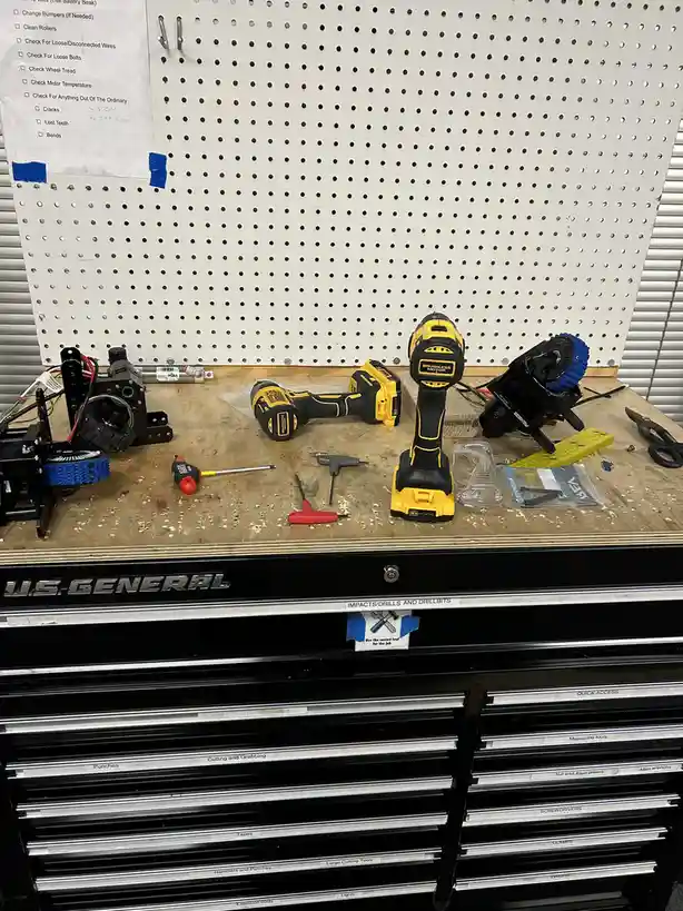 A cluttered workshop workbench displays various tools including two yellow and black DeWalt power drills, screwdrivers, and…