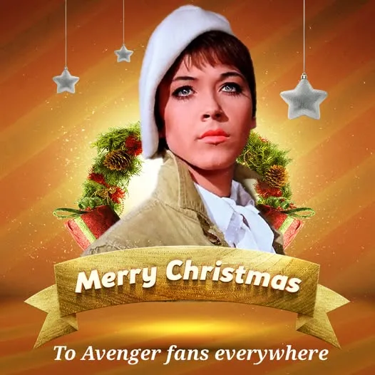 A woman with short dark hair and a white hat is framed by Christmas wreaths and hanging silver stars against a warm orange…