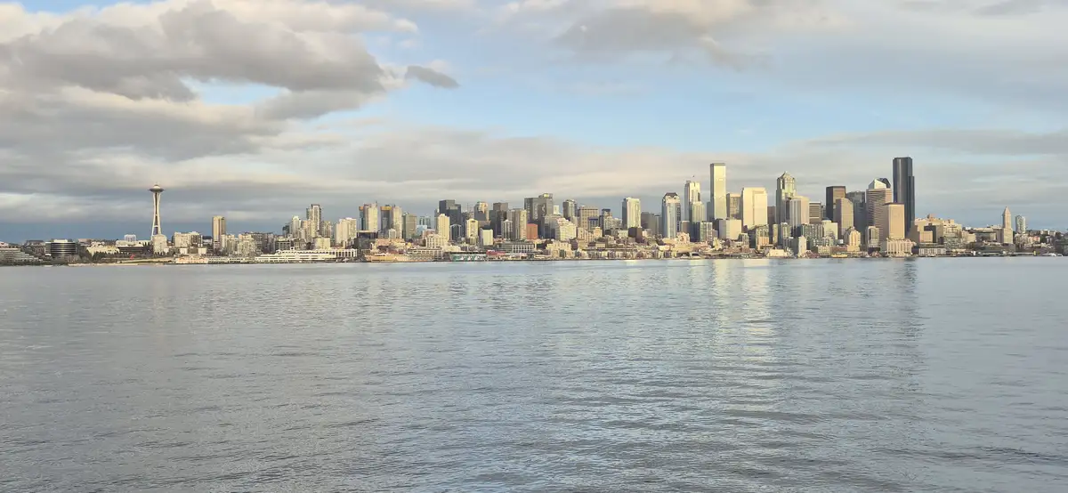 A panoramic view of the Seattle skyline across a body of water, featuring the Space Needle on the left and numerous…