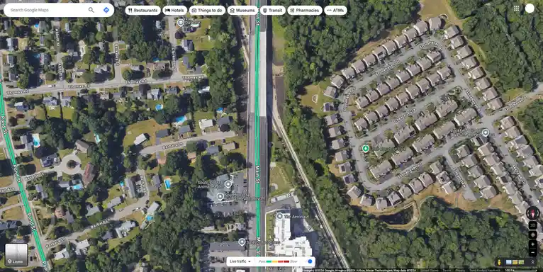 a google maps satellite view shows a wide highway running vertically through a suburban neighborhood, with traffic data…