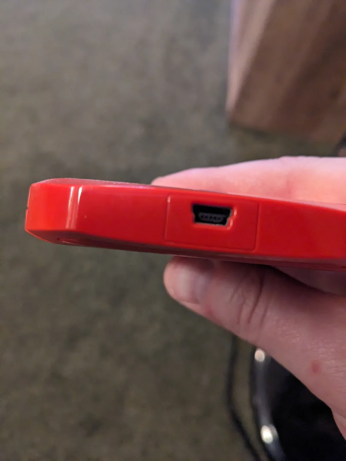 A close-up photo shows a hand holding a red phone case, with a USB-C port visible on its side. The overlaid text reads 'this…