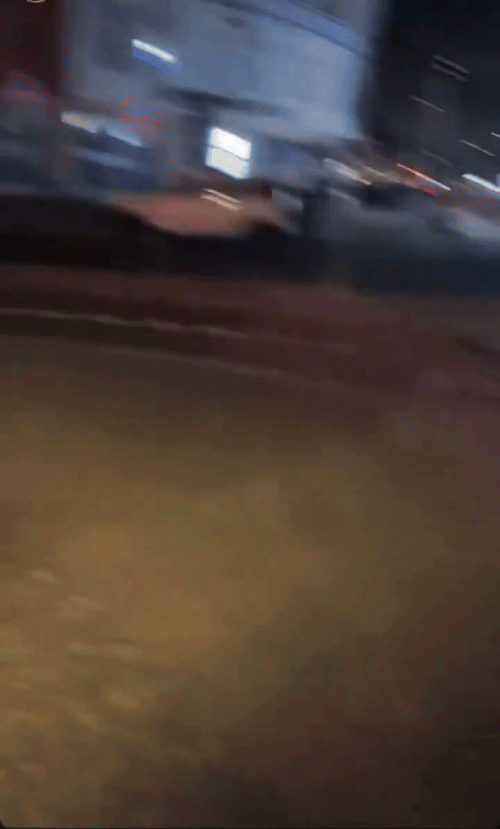 A nighttime street scene collage showing a car exploding with sparks and fire, people running away, and shaky camera footage…