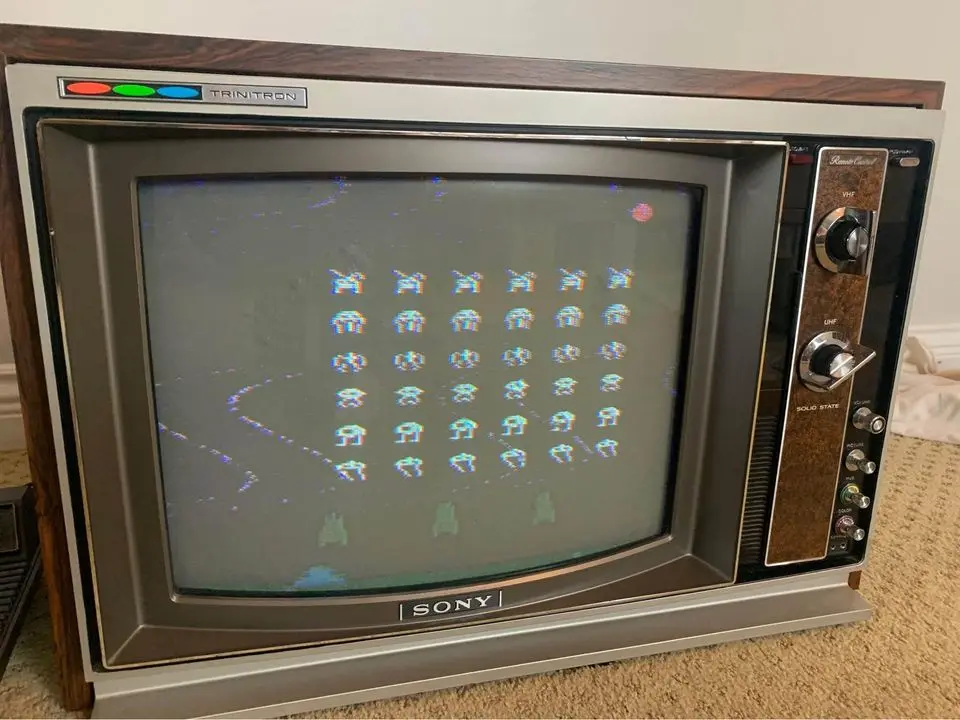 A vintage Sony Trinitron CRT television displays the classic arcade game Space Invaders, showing rows of alien invaders on…