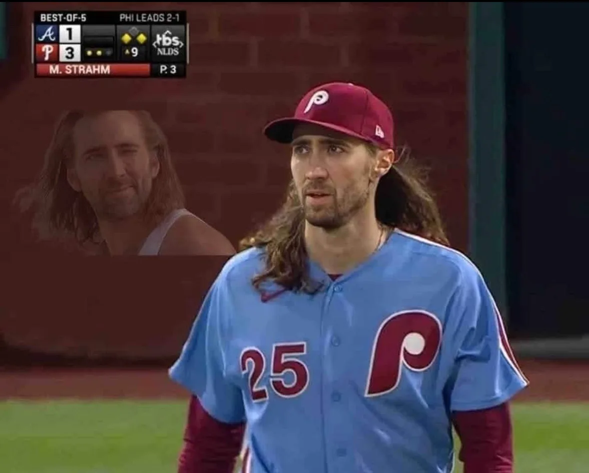 A baseball player wearing a light blue Philadelphia Phillies jersey with the number 25 and a maroon cap stands on a field…