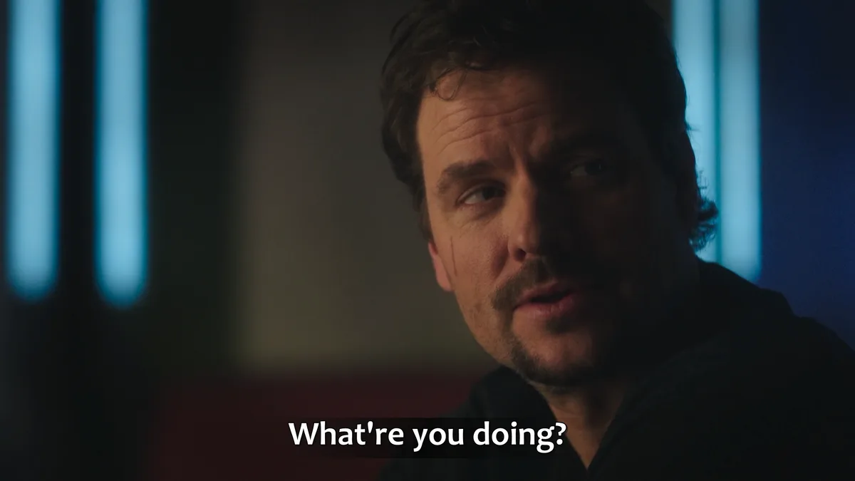 A close-up shot of actor David Harbour with a concerned, slightly confused expression, looking off to the side. He has a…