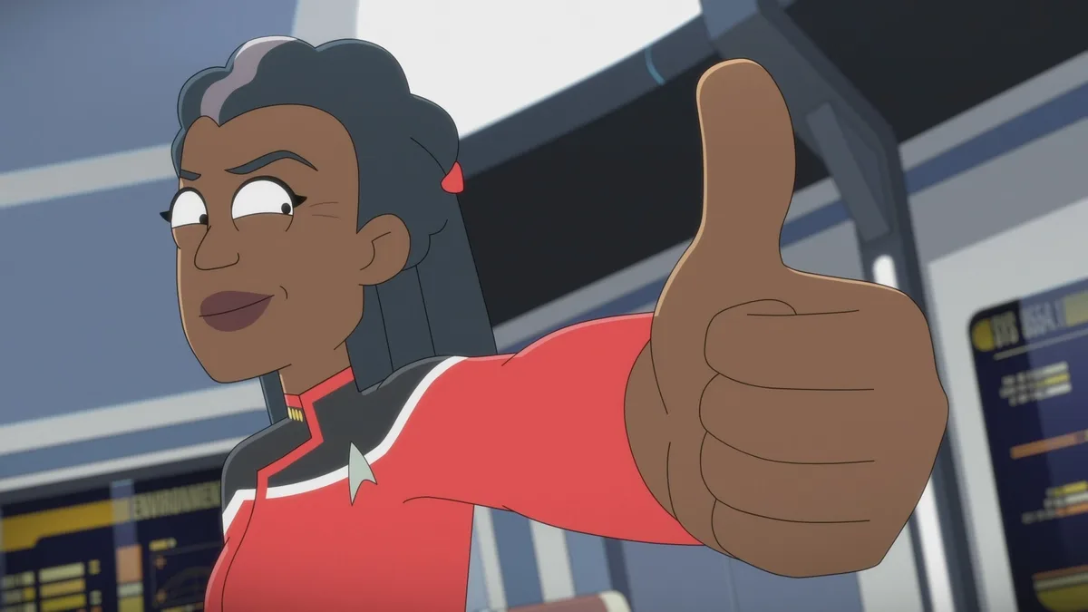 An animated woman in a red Starfleet uniform gives a thumbs-up while looking sideways with a smug expression. The overlaid…