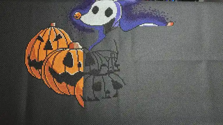 A close-up of a dark gray fabric featuring a pixelated cross-stitch design of Jack Skellington from The Nightmare Before…