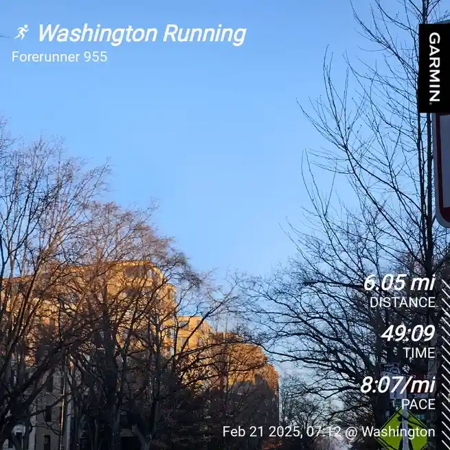 A screenshot of a Garmin Forerunner 955 running watch displaying a workout summary over a photo of bare trees and buildings…