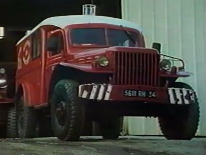 A vintage red and white fire truck with large tires and a prominent grille is shown parked indoors. The overlaid text reads…
