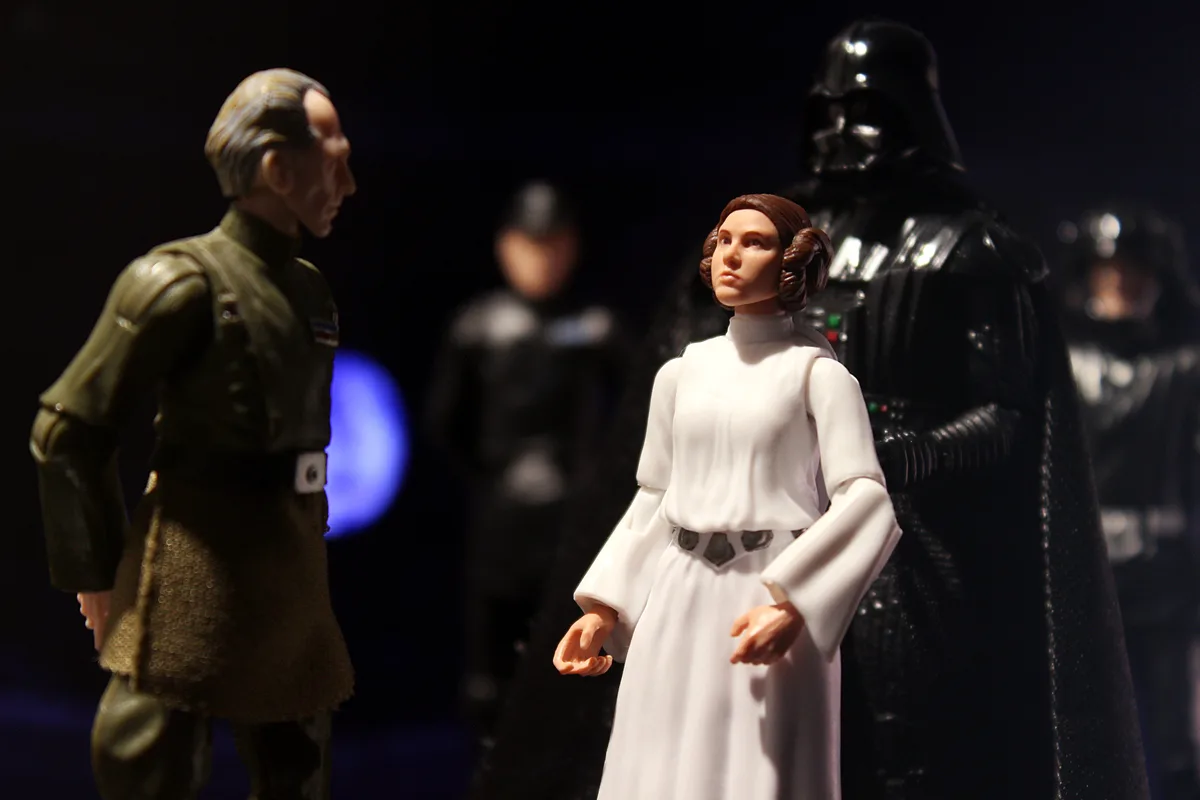 A photo of Star Wars action figures shows Princess Leia in a white dress standing between a green-uniformed officer and…