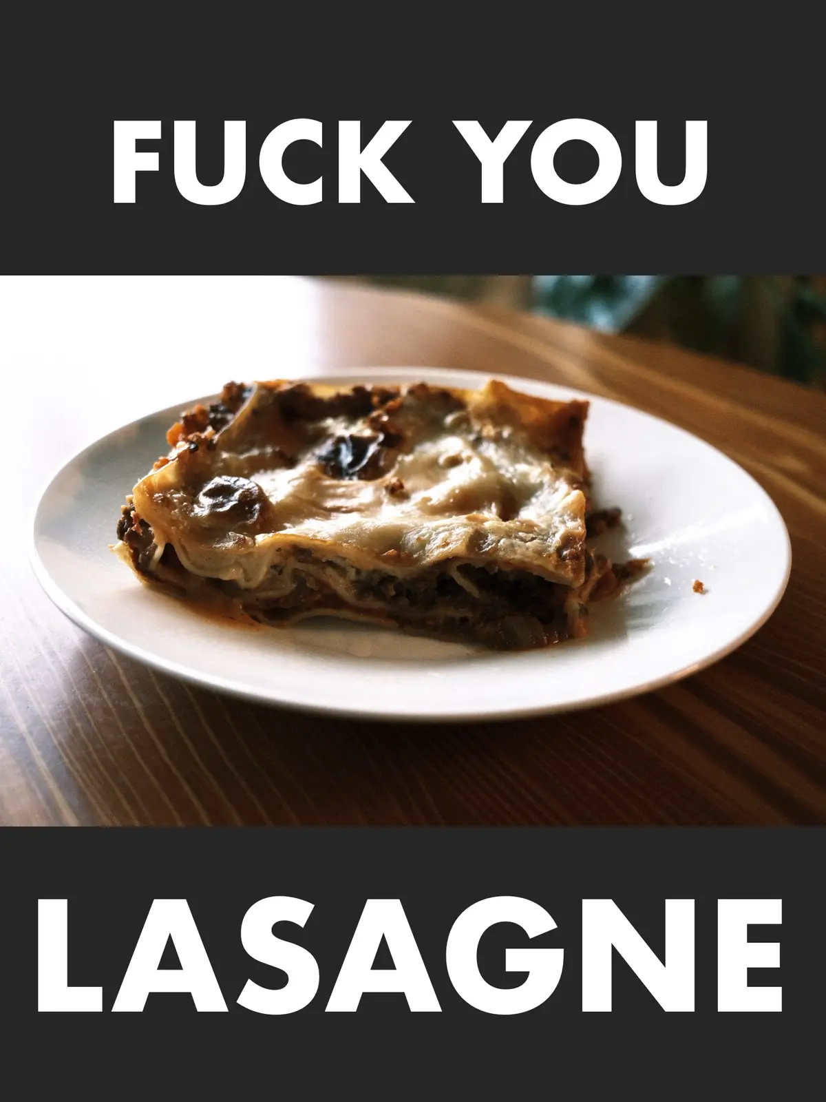 A close-up photo shows a single slice of lasagne on a white plate, resting on a wooden table. The lasagne has a…